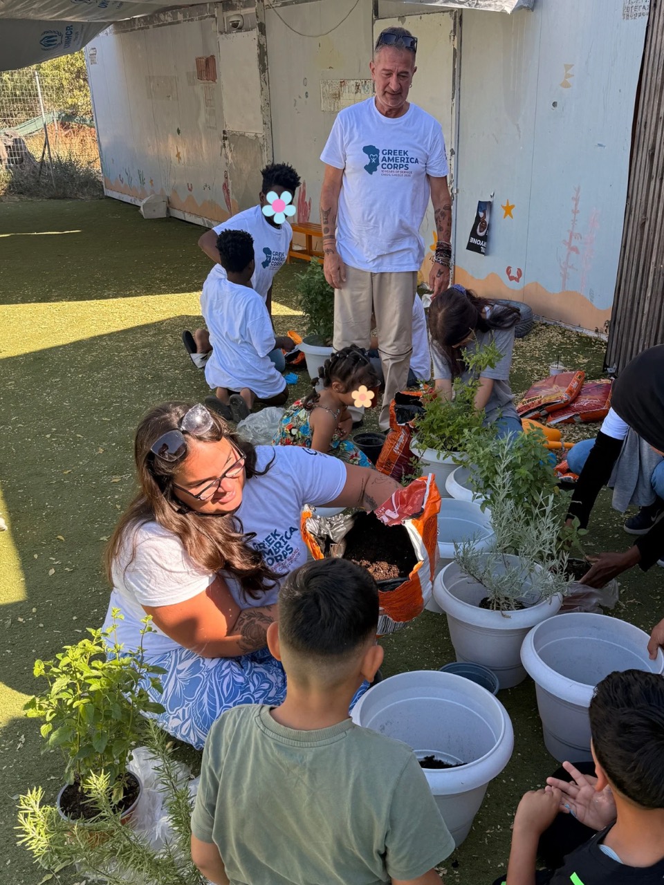 Children and Greek America Corps participants plant herbs in pots outdoors.