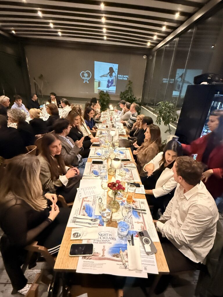 Guests seated at a long dinner table during the Athens benefit.