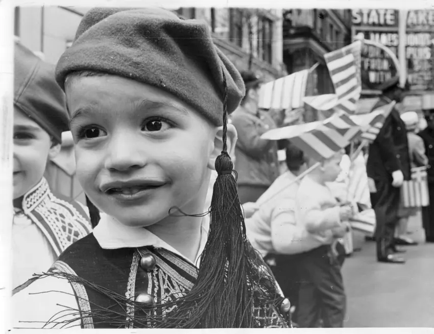 A smiling child wearing traditional dress at a parade