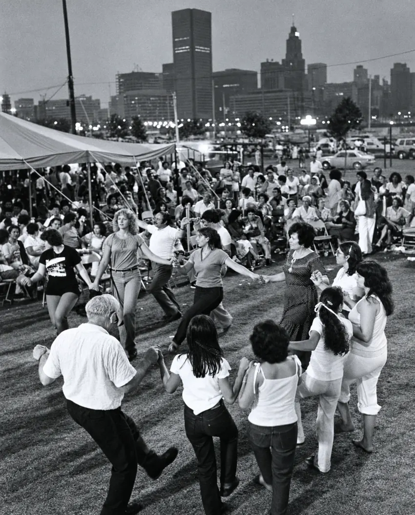 A circle of dancers at an outdoor community celebration